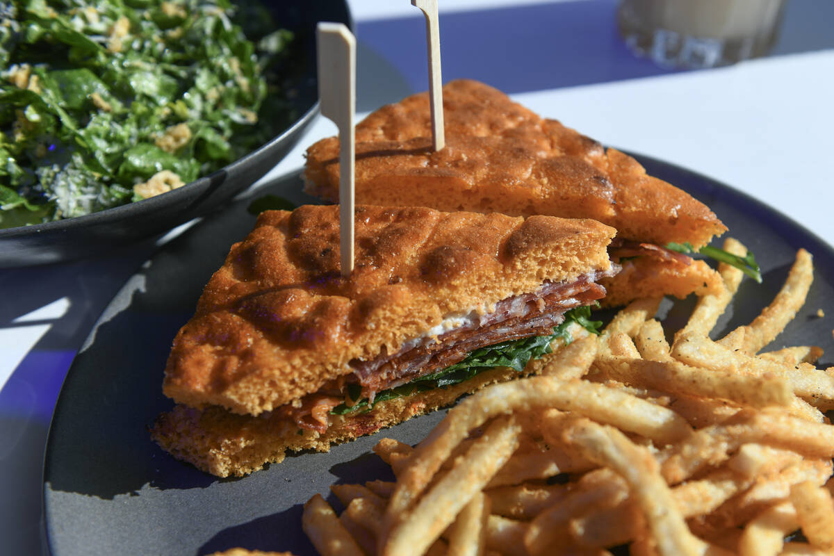 The Salted Focaccia Genovese sandwich with fries and a limoncello caesar salad are seen during ...