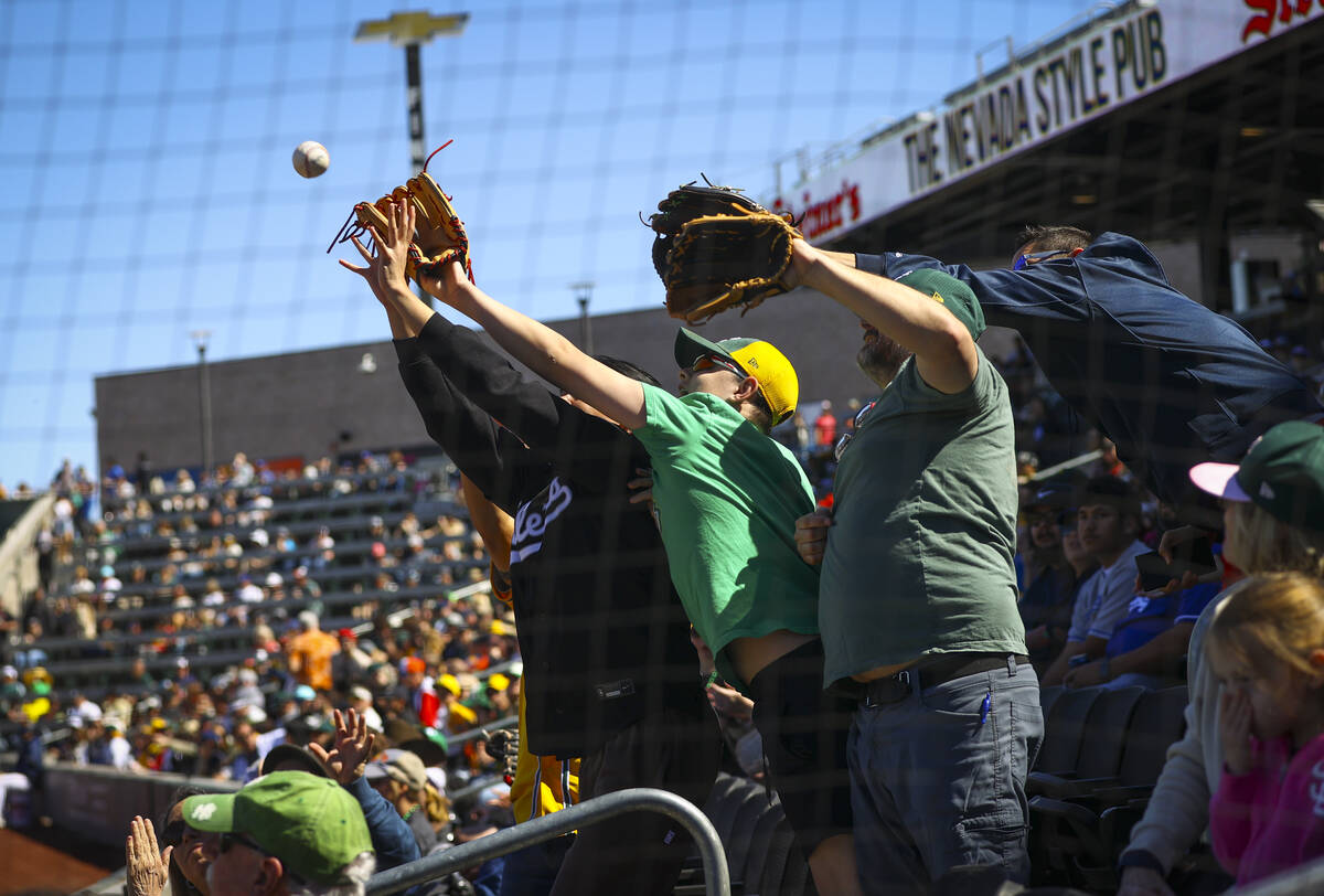 Baseball fans vie for a baseball during a Big League Weekend baseball game between the Athletic ...
