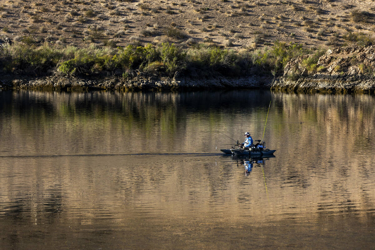 The Colorado River shimmers about a boater fishing after sunrise as it winds its way about Will ...