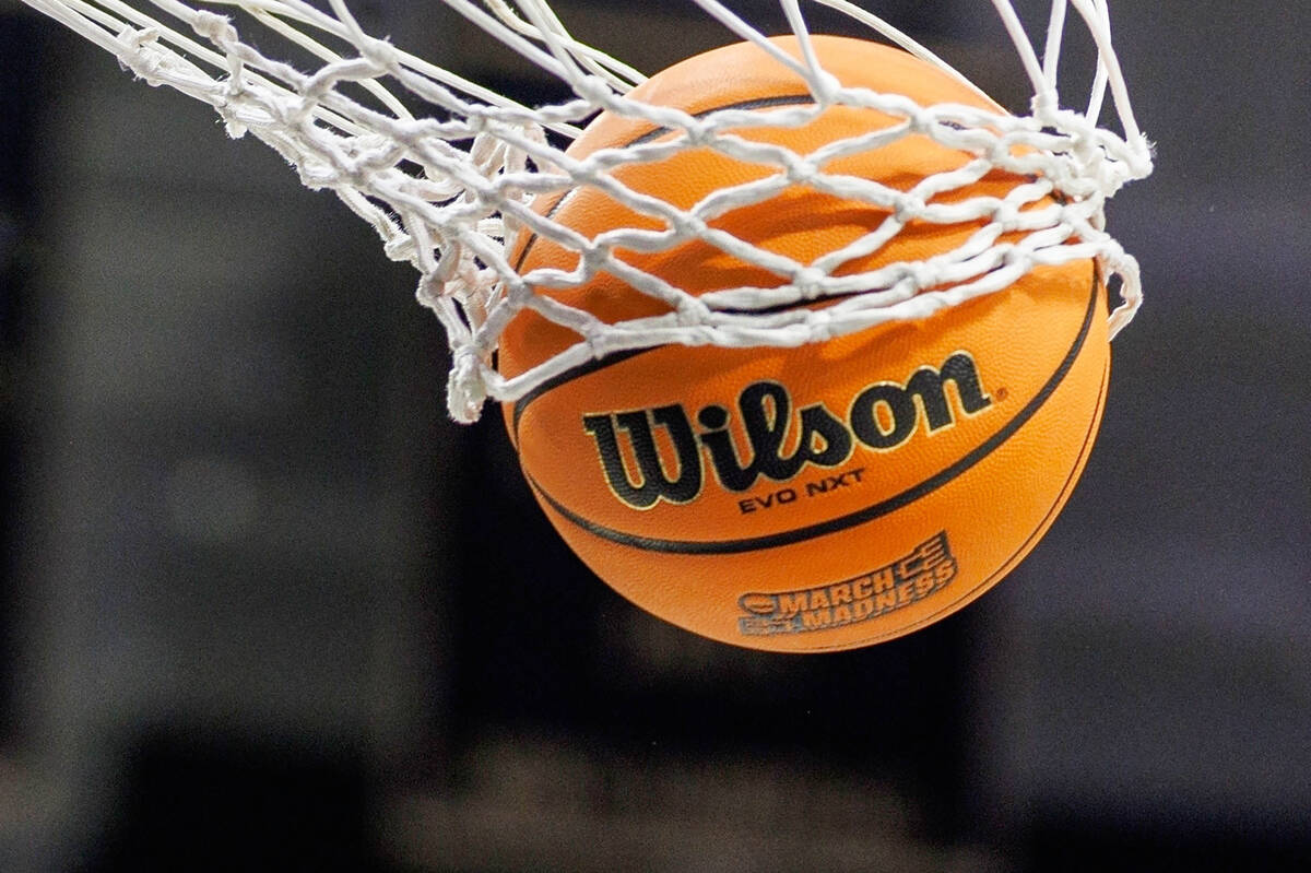 FILE - A basketball with a March Madness logo is seen going through a net prior to a second rou ...