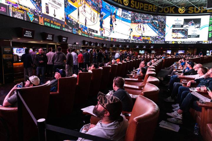 Guests watch on the big screens the first day of the NCAA basketball tournament at the Sports B ...