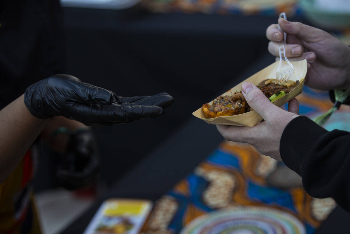An attendee holds a plate from Chef Oulay Fisher of Calabash African Kitchen during Vegas Unstr ...