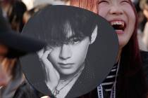 A K-pop fan smiles prior to the BTS World Tour concert outside Tokyo Dome Friday, April 17, 202 ...
