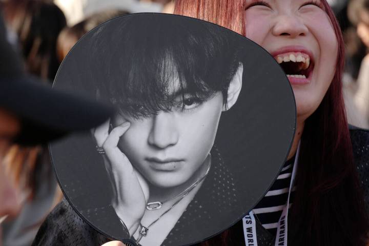 A K-pop fan smiles prior to the BTS World Tour concert outside Tokyo Dome Friday, April 17, 202 ...