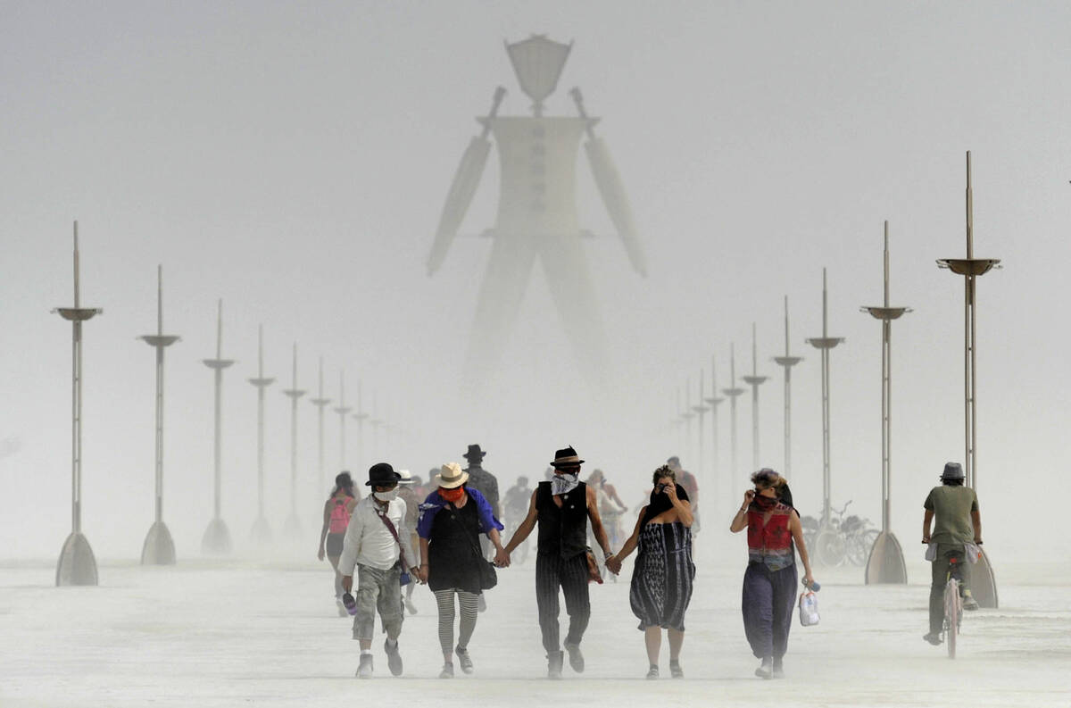 FILE - In this Aug. 29, 2014 file photo, Burning Man participants walk through dust at the annu ...