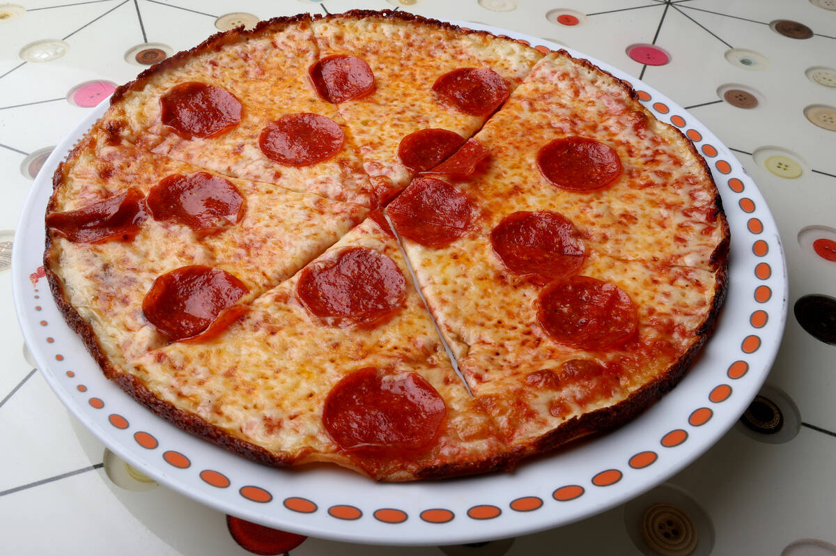 A thin-crust pepperoni pizza with a charred edge served on a plate at Boom Bang Fine Foods and Cocktails