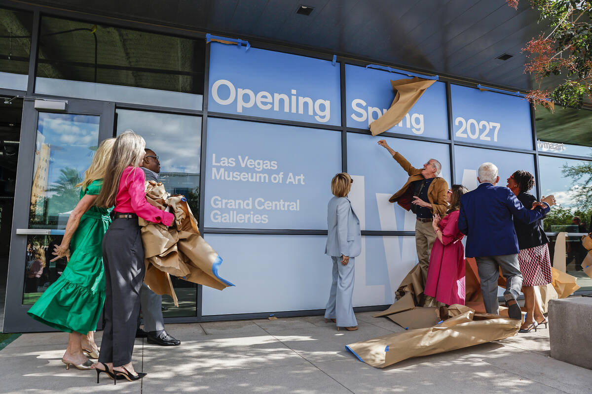 Guests pull brown paper off the windows of Grand Central Galleries in Symphony Park, revealing signs that read Opening Spring 2027, Las Vegas Museum of Art